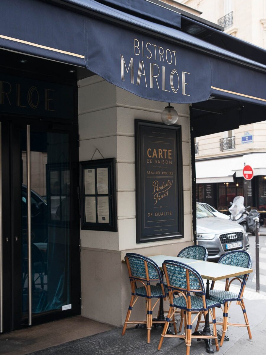 Terrasse extérieur du restaurant Le Marloe de Paris. Chaises en cannage par Maison Gatti. Store et panneaux décor bleu marine.