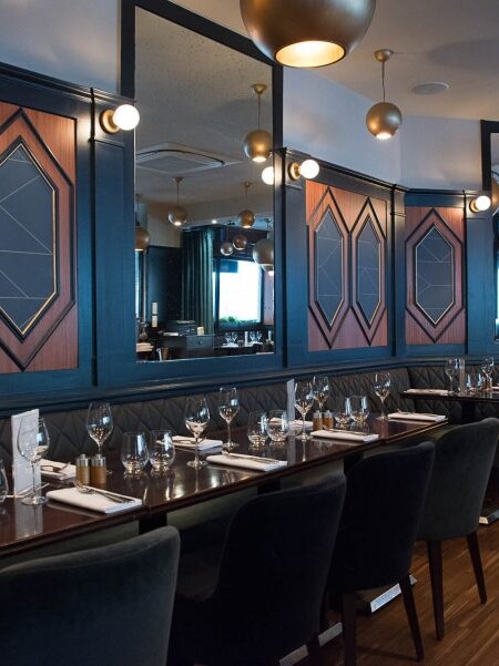 Intérieur du restaurant Le Marloe de Paris avec banquette en cuir matelassée et panneaux décoratifs de bois au motif hexagonal.