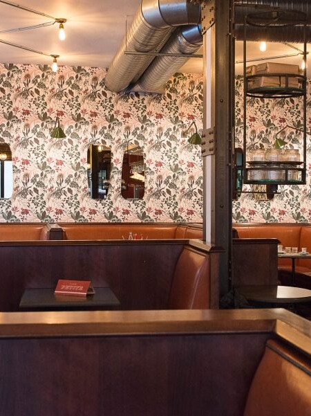 Intérieur du Café Petite à Paris avec sa banquette en cuir naturelle et papier peint fleuris décoration par le Studio Emma Roux