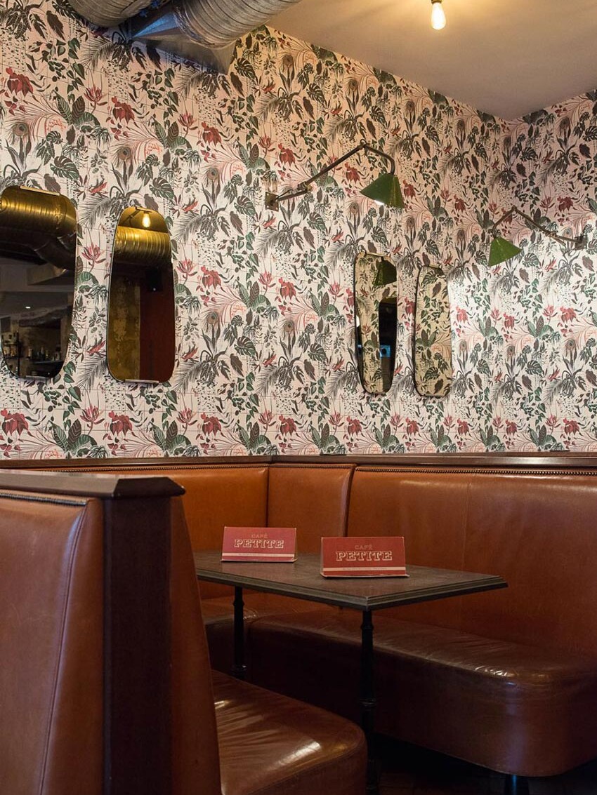 Intérieur du Café Petite à Paris avec sa banquette en cuir naturelle et papier peint fleuris décoration par le Studio Emma Roux