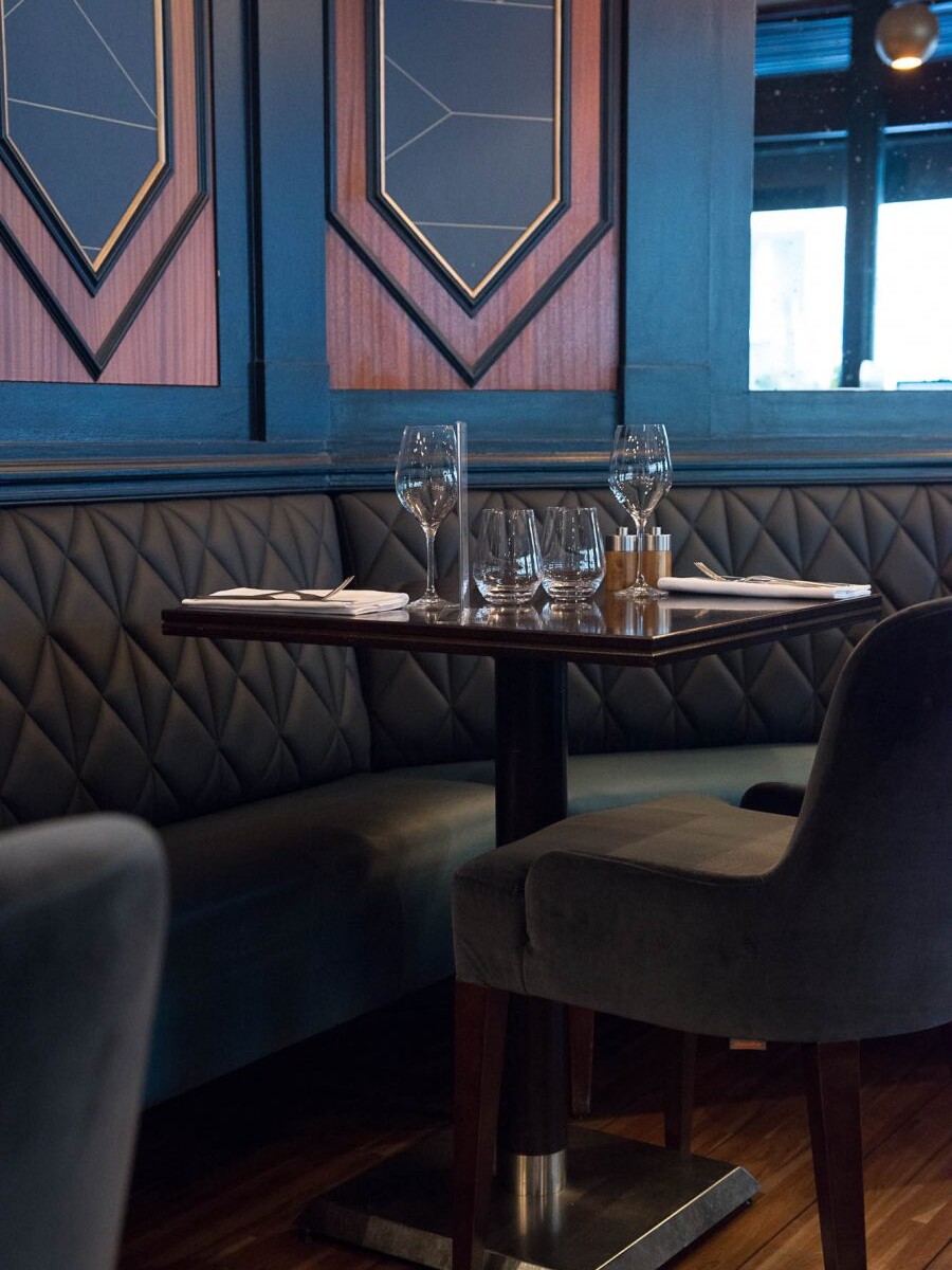 Intérieur du restaurant Le Marloe de Paris avec banquette en cuir matelassée et panneaux décoratifs de bois au motif hexagonal
