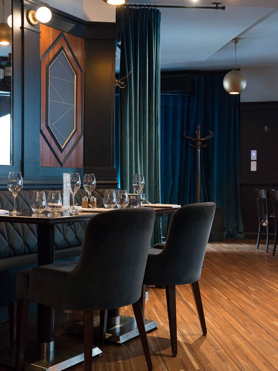 Intérieur du restaurant Le Marloe de Paris avec banquette en cuir matelassé, parquet et panneaux décoratifs de bois au motif hexagonal