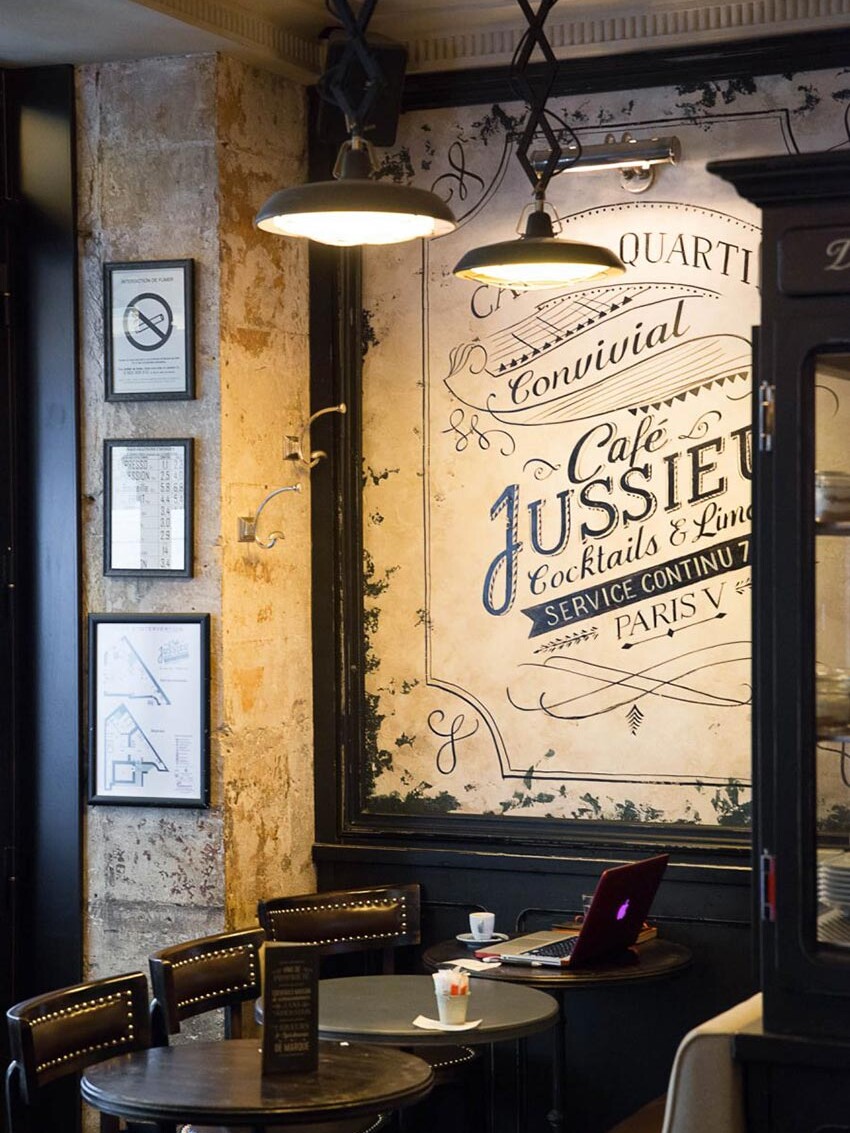 Intérieur du Café Jussieu de Paris avec son panneau décor, ses suspensions croisillon et ses assises en cuir.
