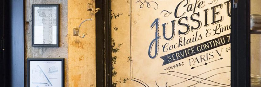 Intérieur du Café Jussieu de Paris avec son panneau décor, ses suspensions croisillon et ses assises en cuir.