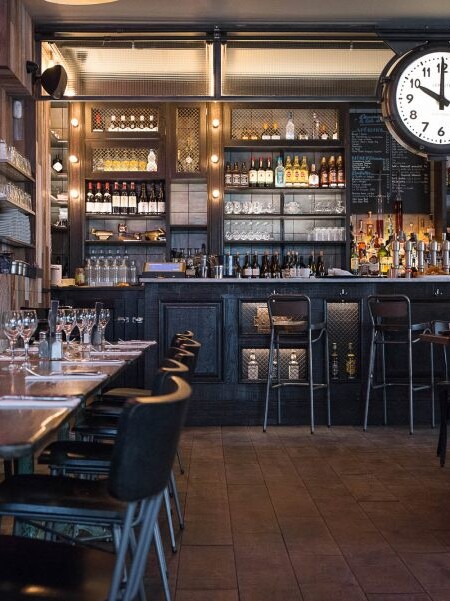 Intérieur de la rôtisserie Maison Becquey, avec son comptoir en bois, sa banquette de cuir, son cadran suspendu et son parquet. Décoration par le Studio Emma Roux