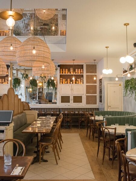 Intérieur de la pizzeria Simonetta à Paris. Banquettes en velour et cuir. Luminaires et plantes en suspension. Miroir au plafond. Décoration par le Studio Emma Roux