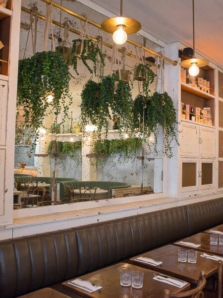 Intérieur du restaurant Simonetta, luminaires dorés et plantes suspendus. Assises des chaises et de la banquette en cuir. Décoration par le Studio Emma Roux.