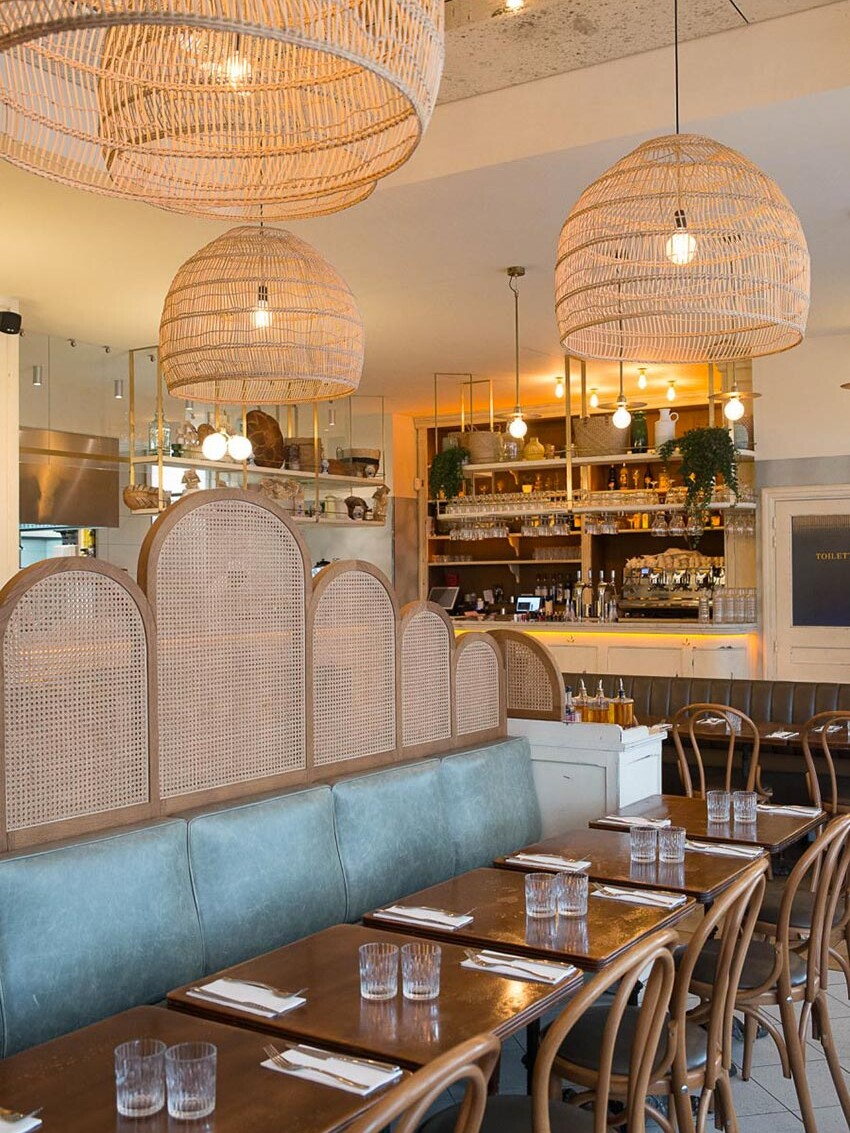Intérieur du restant Simonetta de Paris avec des luminaires naturels en suspension. On aperçoit au fond le comptoir en bois blanc vieilli. Décoration par le Studio Emma Roux