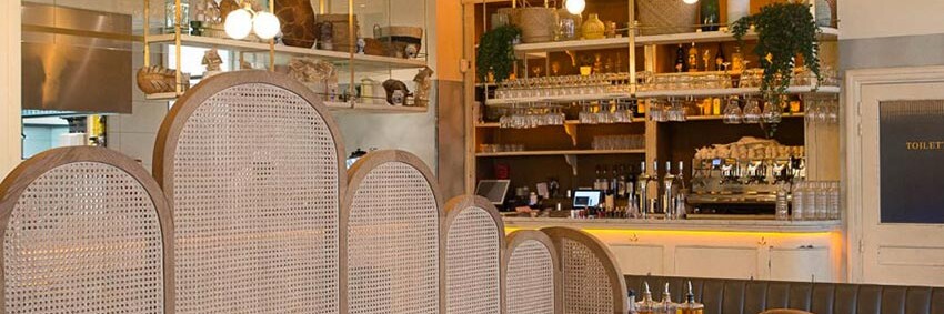 Intérieur du restant Simonetta de Paris avec des luminaires naturels en suspension. On aperçoit au fond le comptoir en bois blanc vieilli. Décoration par le Studio Emma Roux