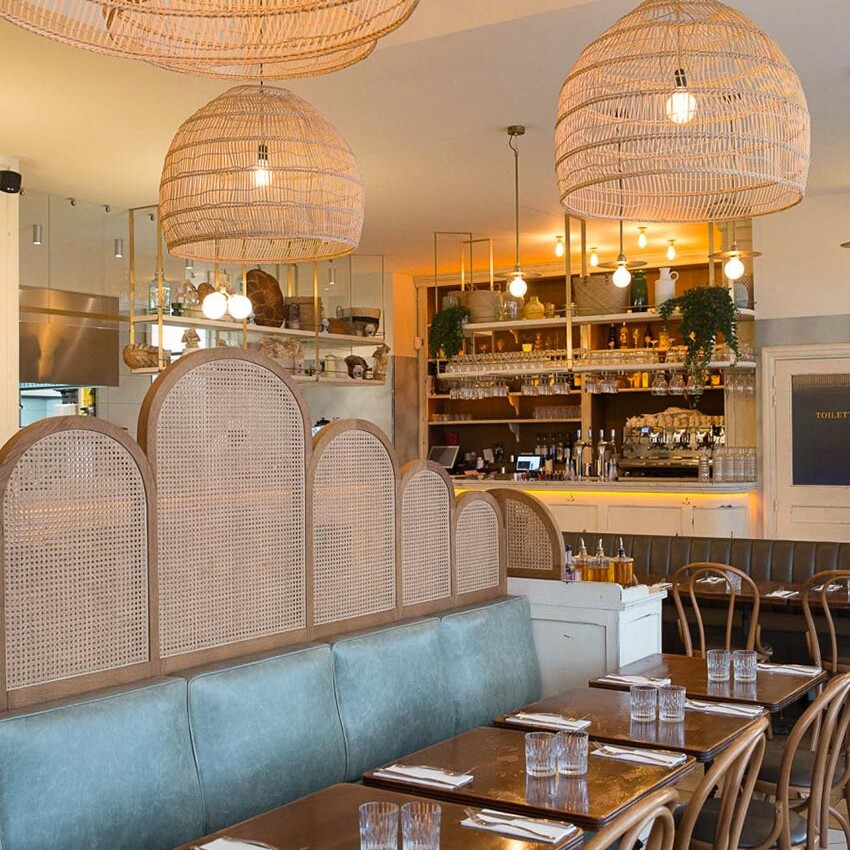 Intérieur du restant Simonetta de Paris avec des luminaires naturels en suspension. On aperçoit au fond le comptoir en bois blanc vieilli. Décoration par le Studio Emma Roux