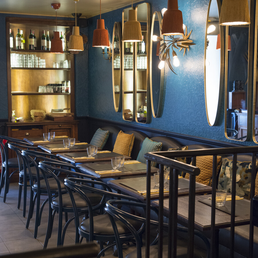Restaurant Chez Plumeau à Montmartre - Décoration Studio Emma Roux. Jeux de miroir, appliques vintage en laiton, coussins à motifs, suspensions à frange.