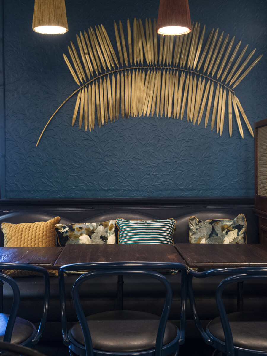 Restaurant Chez Plumeau à Montmartre - Décoration Studio Emma Roux. Applique décorative en laiton, coussins à motifs.